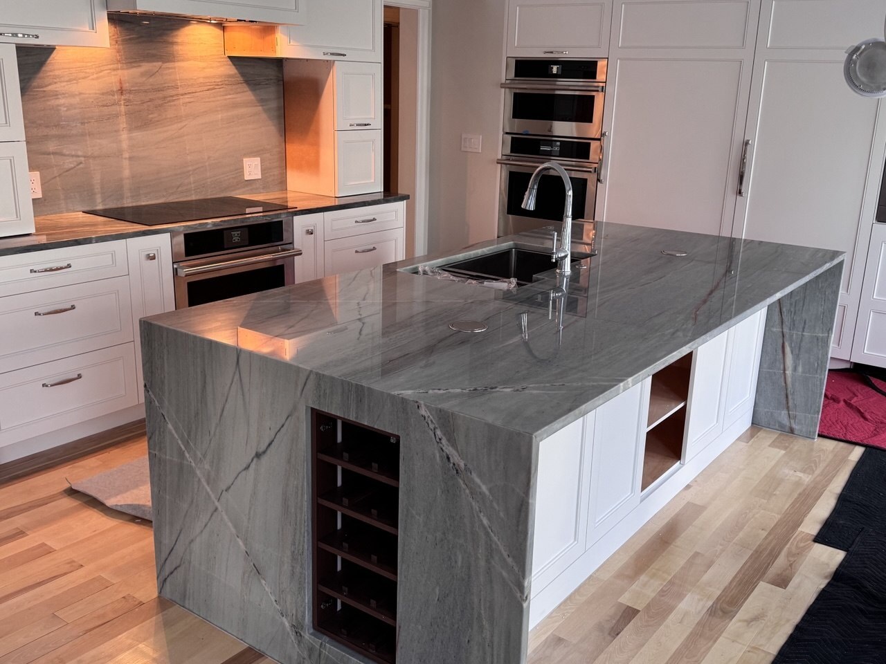 Completed kitchen with natural-stone waterfall island and full-height backsplash